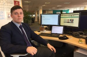 Blake Meyrick sitting in front of his desk with laptop and dual monitors