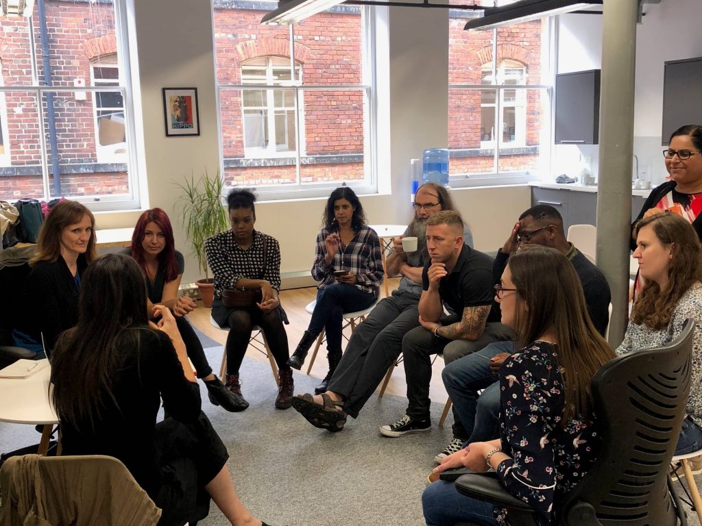 A group of user researchers sitting in a circle having an in depth discussion