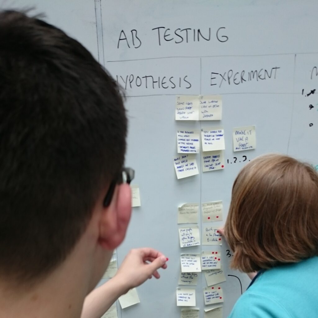A male and female place post it notes on a whiteboard