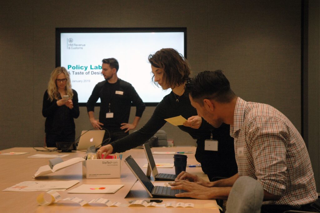 Two males and two females standing at a large conference table in conversation