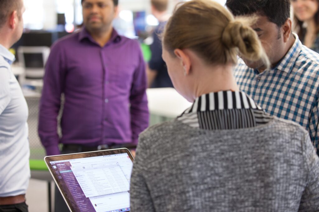 A group of people standing around a laptop in discussion