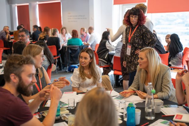 Image of attendees sitting in groups at tables having discussions