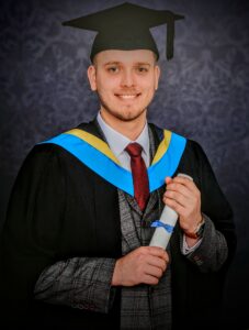 James in his graduation gown holding his certificate